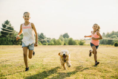 young girls running through a field working on Labradoodle training